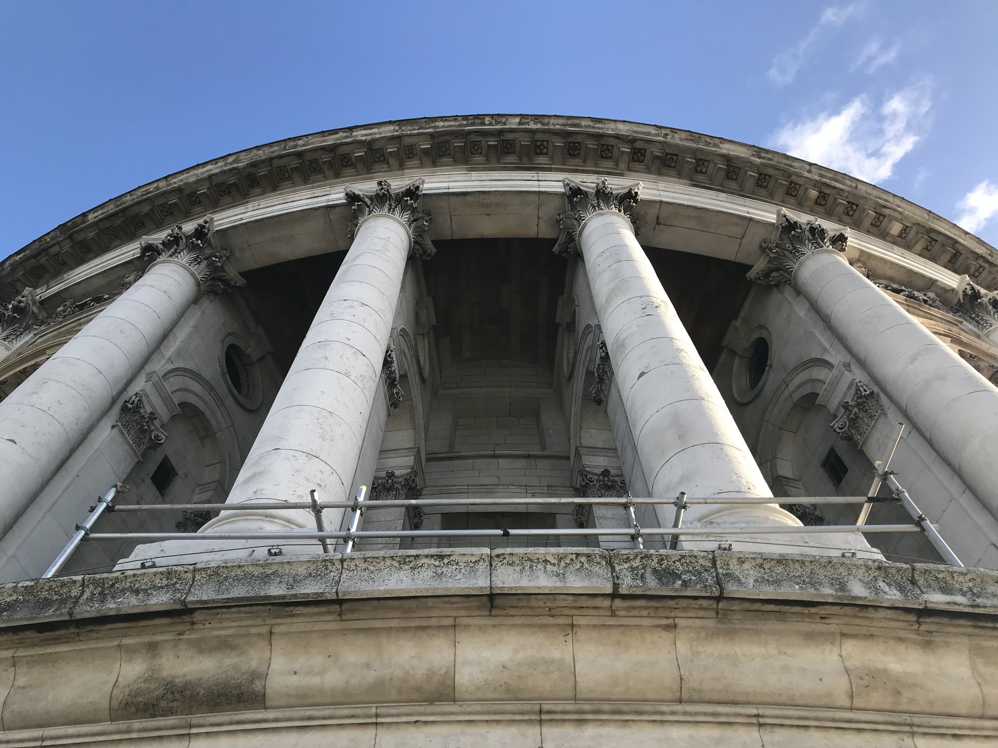 Classical stone columns and dome detail against a blue sky